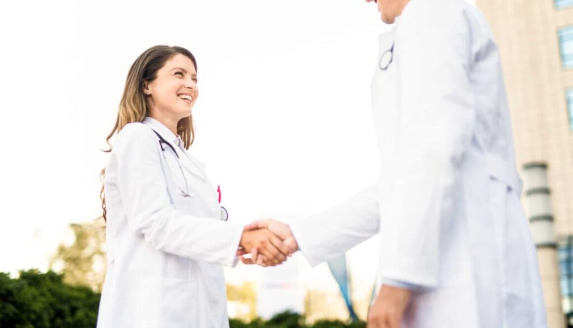Young female healthcare worker shaking hands with doctor. Bringing on a New Provider? The Importance of Not Waiting For Credentialing