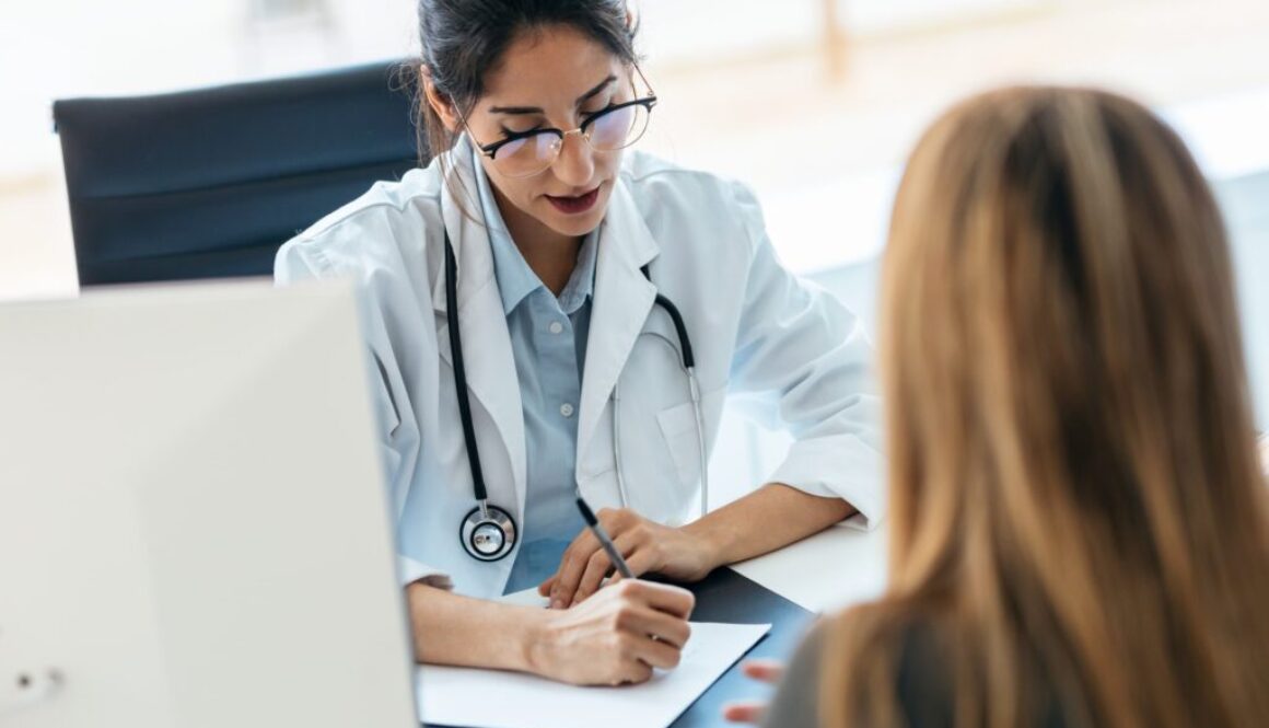 Beautiful cheerful female doctor talking while explaining medical treatment to patient in the consultation.