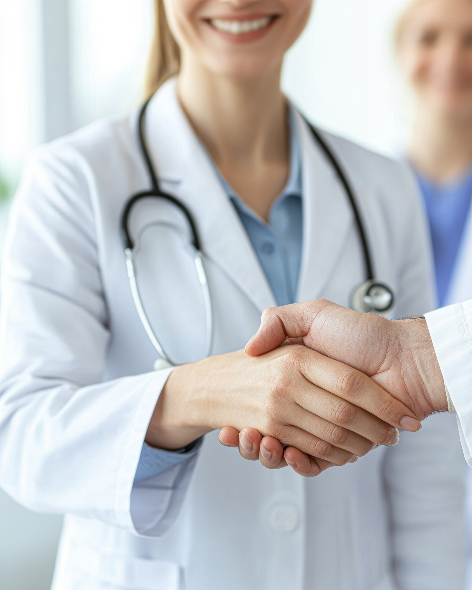 A healthcare professional shakes hands with a client, symbolizing trust and partnership in a medical setting. A healthcare professional shakes hands with a client, symbolizing trust and partnership in a medical setting.