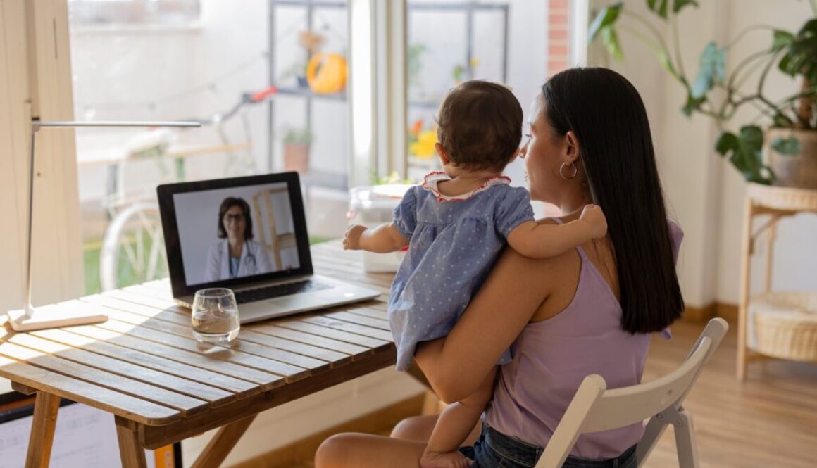 mother on her back with her daughter in her arms sitting on a video call with the doctor - virtual appointment, medicine at home